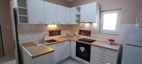 a kitchen with white cabinets and a sink and a refrigerator at Smokva in Zadar