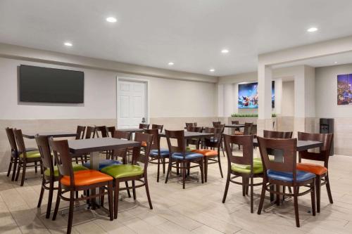 a restaurant with tables and chairs and a flat screen tv at Days Inn & Suites by Wyndham Anaheim At Disneyland Park in Anaheim