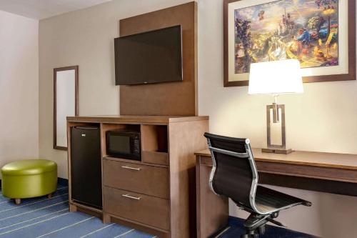 a room with a desk with a television and a chair at Days Inn & Suites by Wyndham Anaheim At Disneyland Park in Anaheim