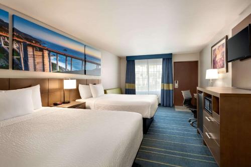 a hotel room with two beds and a television at Days Inn & Suites by Wyndham Anaheim At Disneyland Park in Anaheim