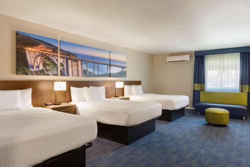 a hotel room with two beds and a painting on the wall at Days Inn & Suites by Wyndham Anaheim At Disneyland Park in Anaheim