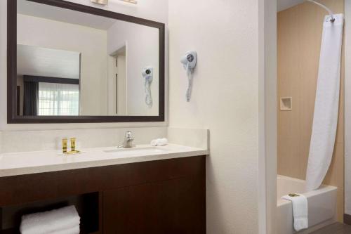 a bathroom with a sink and a mirror at Days Inn & Suites by Wyndham Anaheim At Disneyland Park in Anaheim