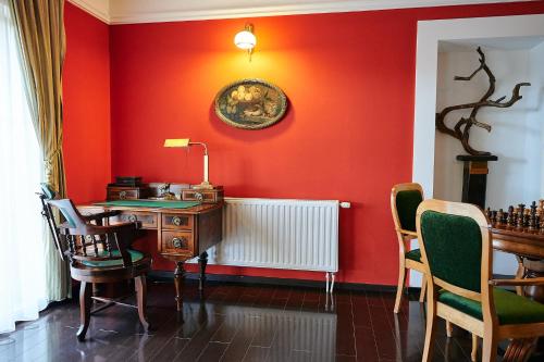 a room with a red wall with a desk and chairs at Saciova Hills in Saciova