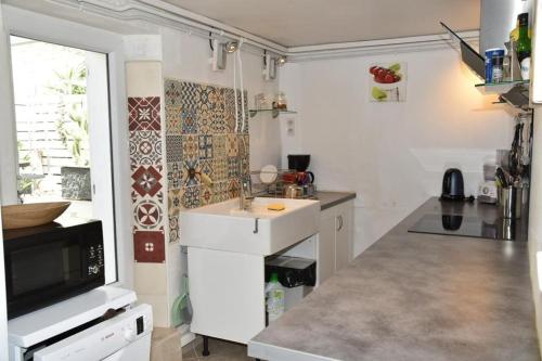 a white kitchen with a sink and a tv at Rez de chaussée de Villa Marseille 9ème in Marseille