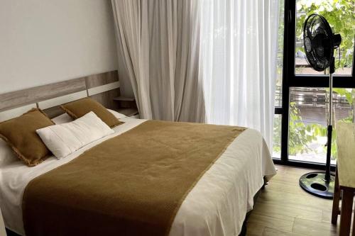 1 dormitorio con 1 cama y ventana con ventilador en Residencias San Lorenzo en Mar del Plata