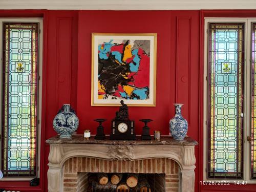 a fireplace in a red room with a painting at CHATEAU DE BRINVILLE in Saint-Sauveur-sur-École
