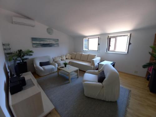 a living room with white couches and a tv at Apartman Marina sa parkingom in Jelsa