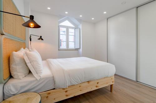 a bedroom with a bed with white sheets and a window at Amazing Setúbal in Setúbal