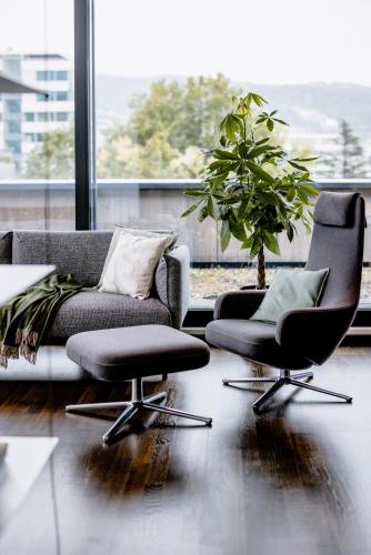 a living room with a couch and two chairs and a potted plant at THE FLAG Zürich in Zürich