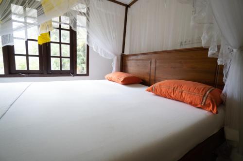 - un lit avec deux oreillers orange dans une chambre avec une fenêtre dans l'établissement Happy Rest By Chill House, à Unawatuna