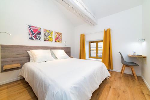 - une chambre avec un grand lit blanc et une chaise dans l'établissement Tintin - Locationtournus, à Tournus