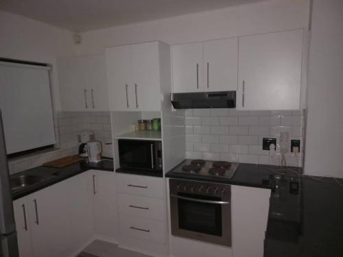 uma cozinha com armários brancos e um forno com placa de fogão em Rachimy em Walvis Bay