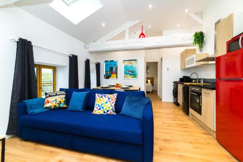 un salon avec un canapé bleu et une cuisine dans l'établissement Tintin - Locationtournus, à Tournus