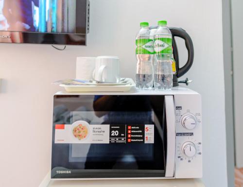 a microwave with bottles of water on top of it at High5 Guesthouse in Pattaya Central
