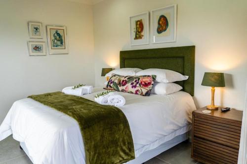 a bedroom with a large white bed with a green headboard at Verdant Hills in Reebok
