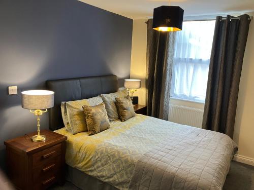 a bedroom with a bed with a lamp and a window at THE OCEAN SUITE - 2 minute walk to the lovely beach front promernade of llandudno in Llandudno