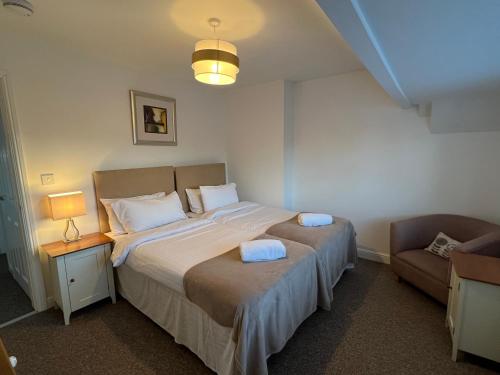 um quarto com uma cama grande e uma cadeira em First floor flat with parking em Wheatley