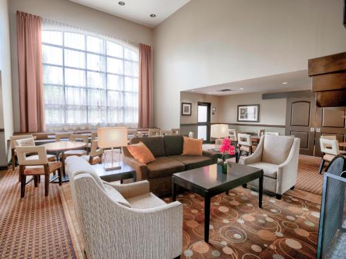 a living room with couches and tables and chairs at Staybridge Suites West Edmonton, an IHG Hotel in Edmonton