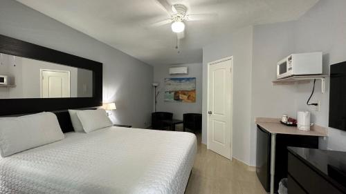 a bedroom with a white bed and a microwave at White Horse Motel in Lake Worth