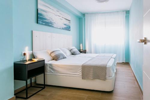 um quarto com uma cama branca e uma parede azul em A Casa Martinez Playa Sin Ascensor em Mareny Barraquetas