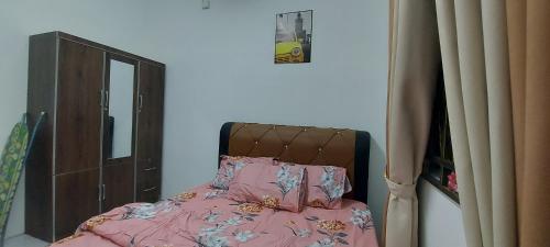 a bedroom with a bed with pink sheets and a mirror at Myrol Homestay Kulim in Kulim