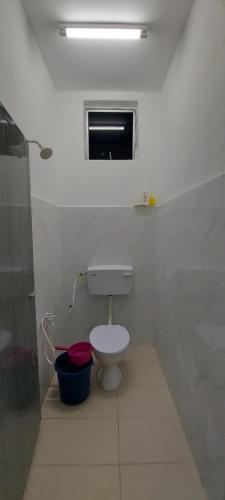 a white bathroom with a toilet and a window at Myrol Homestay Kulim in Kulim