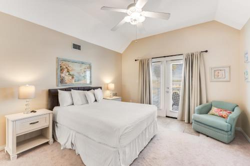 a bedroom with a white bed and a blue chair at Beach Haven by Meyer Vacation Rentals in Gulf Shores
