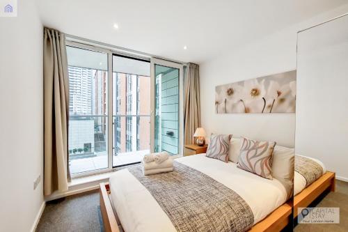 um quarto com uma cama e uma grande janela em Fully Serviced Two Bed Apartment by ExCeL & O2 em Londres