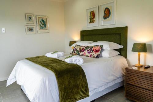 a bedroom with a large white bed with a green headboard at Verdant Hills in Reebok