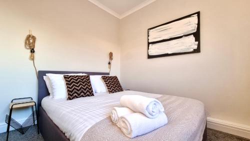 1 dormitorio con 1 cama con toallas en The Loft by Switchback Stays, en Cardiff
