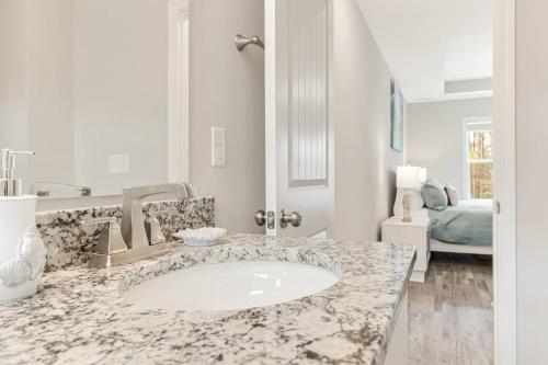 een witte badkamer met een marmeren wastafelblad bij Ruff-Tide in Oak Island