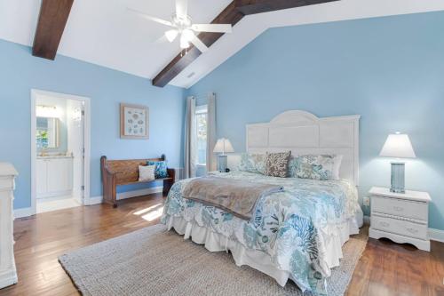 een blauwe slaapkamer met een bed en een plafondventilator bij The Cottage at Arbor Creek in Southport