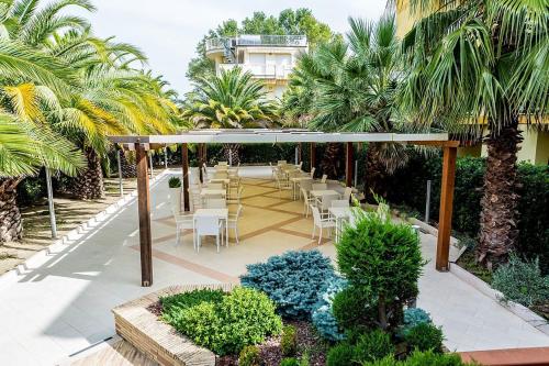 un patio con mesas, sillas y palmeras en Hotel Vittoria, en Vasto