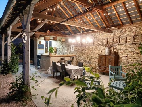 eine Terrasse mit einem Tisch, Stühlen und einer Steinmauer in der Unterkunft La grenouille amoureuse in Menat