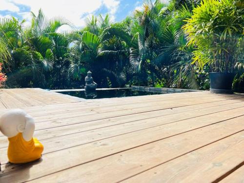 um pato de brinquedo sentado num deque de madeira perto de uma piscina em Ô Palm : dans un petit écrin de verdure em Saint-Joseph