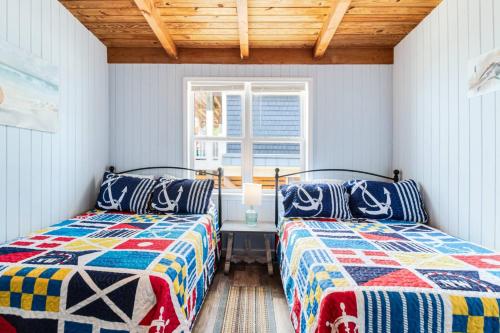 two beds in a room with a window at Somewhere on a Beach in Oak Island