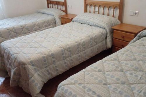 três camas num quarto com uma cómoda de madeira em Casa Agner em Adsubia