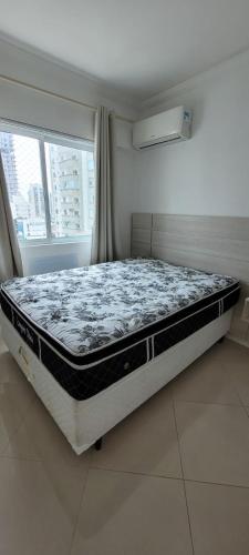 een slaapkamer met een bed in een kamer met een raam bij Apto 2 suítes próximo à Roda Gigante in Balneário Camboriú