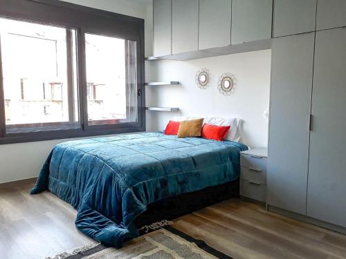 1 dormitorio con cama con sábanas azules y ventana en Carla D. en Coimbra
