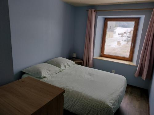 um pequeno quarto com uma cama e uma janela em ô Doux Comtois em Les Fourgs