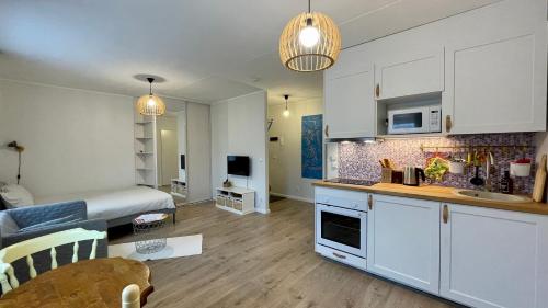 a kitchen with white cabinets and a living room at Studio apartment in Pärnu