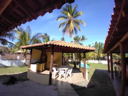 une maison avec une terrasse couverte dotée d'une table et de chaises dans l'établissement Maravilhosa praia do Sargi - BA, à Serra Grande