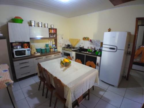 uma cozinha com uma mesa e um frigorífico branco em Maravilhosa praia do Sargi - BA em Serra Grande