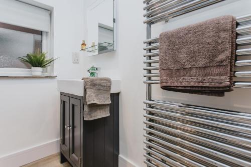 a bathroom with a sink and towels on the wall at Spacious Apartment Near City Centre - Free Parking, Wi-Fi with King Size Bed in Nottingham