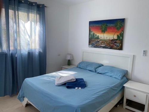 a bedroom with a bed with blue sheets and a window at Sunny Apartment in Bayahibe