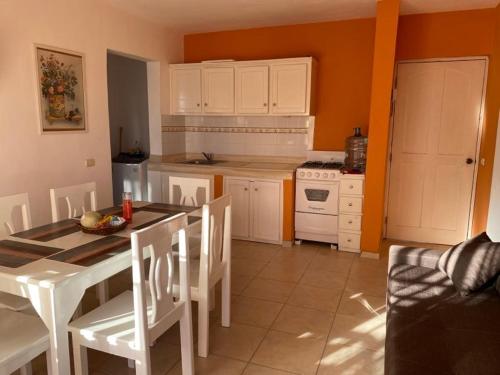 a kitchen with a table and white cabinets and a table and chairs at Sunny Apartment in Bayahibe