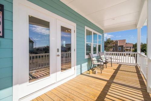 a porch with chairs and tables on a blue house at Sandy Noses in Oak Island