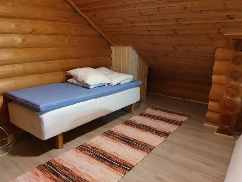 Cama en habitación de madera con 2 almohadas en Pitkämö Canyon Camping Oy, en Kurikka