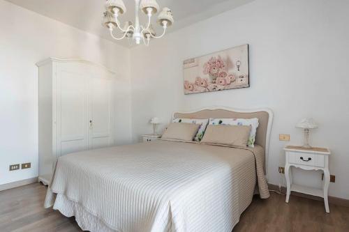 a white bedroom with a bed and a chandelier at Fiesole is Magic in Fiesole