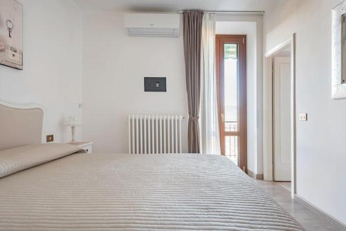 a white bedroom with a large bed and a window at Fiesole is Magic in Fiesole
